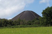 Grande monte preto cônico com árvores em primeiro plano