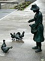 Femme avec des poules et vestiges des remparts