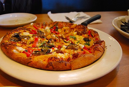 A California Pizza Kitchen Pie with goat cheese, peppers, eggplant, onions, and parsley.