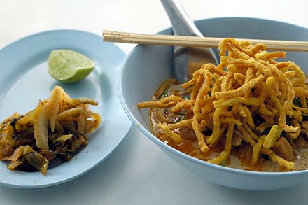 A bowl of Chiang Mai's signature dish, Khao Soi Kai, with pickled cabbage and lime to add to taste