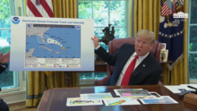 A frame from the above video with Trump displaying the altered map. Trump holding altered Dorian forecast map.png