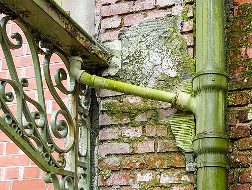 Rusted rain gutter with funnel, bends and downspout made of cast iron