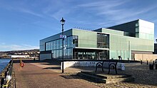 To the left of the two storey entrance foyer, the Cafe & Bar and Gallery Suite above it look over the Clyde, to the right the Main Auditorium stage is under the fly tower. Beacon Arts Centre close view from quay.jpg