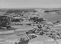 Luftfoto, formentlig fra 1950'erne, af den nordlige del af Nøtterøy med Teie foran og Tønsberg i baggrunden med fjordbassinet Træla til højre. Foto: Widerøe/Vestfoldmuseene