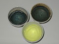 3 Tiegel mit Oxidationsschmelzen als Vorproben und Nachweisreaktionen für Mangan und Chrom: Blaugrün als Manganat, gelb als Chromat)