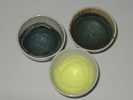 3 Tiegel mit Oxidationsschmelzen als Nachweisreaktion für Mangan und Chrom: Blaugrün als Manganat(VI), gelb aus Chromat.