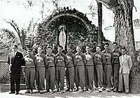 Fotografía en blanco y negro de los espartanos de Orán alineados frente a una estatua de la virgen