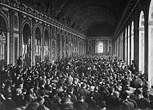 Foto av den mycket långa och breda spegelsalen där en otalig folkmassa står runt människor som sitter i grupper på stolar.
