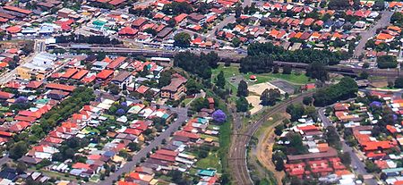 The Wardell Road Junction in 2009. This is now where the heavy rail and light rail lines meet. Dulwich Hill station can be seen top left. The overgrown tracks curving towards the station are now used by the light rail, which opened in 2014. The tracks curving in the other direction became disused when the freight services that had used this line ceased operating. Wardell Road Junction from the air (13113706185).jpg