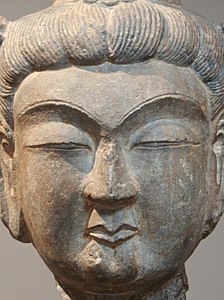 Tête de bodhisattva. Dynastie Tang (618-907), fin VIIe siècle. Grès. Musée Cernuschi[6]