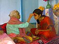 Senior offering Dashain Tika to junior in an urban home
