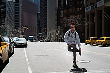 Manhattan, 2018. Modern kick scooters are popular among the young. 7 million Razor scooters were sold in America alone during 2000-2001 Guy on a scooter (44759596865).jpg