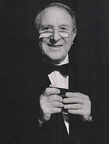 An older man with glasses wearing a suit and bow tie