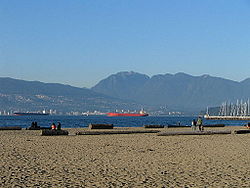 Jericho Beach; napravo se nachází Royal Vancouver Yacht Club, na pozadí je Stanley Park a pohoří North Shore