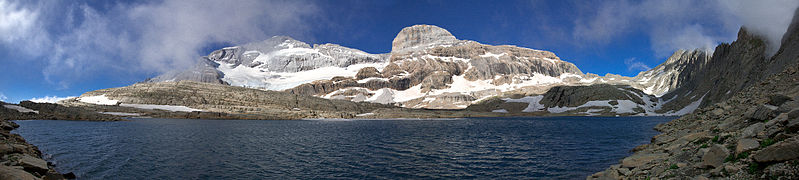 Vue d'un lac de montagne surplombé de sommets enneigés.
