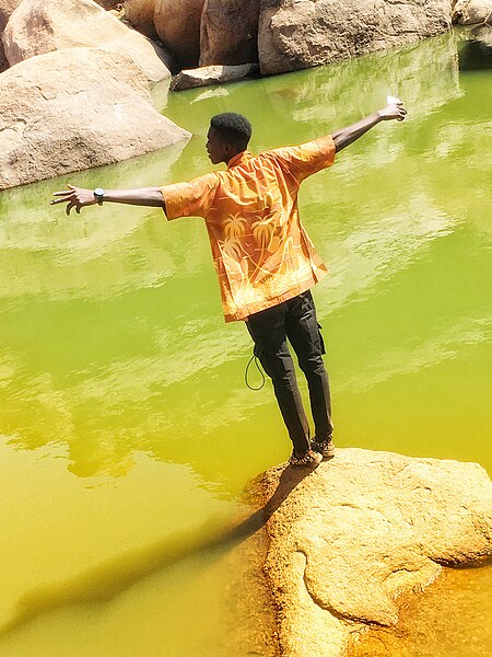 File:Man standing on a rock by the river.jpg