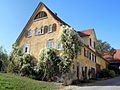 Deutsch: Quereinhaus in Neckartailfingen, Schulberg 17. Putzbau mit klassizistischen Fenstern im Giebeldreieck, geohrte Türrahmung, erste Hälfte des 19. Jahrhunderts erbaut. Denkmal nach § 2 Denkmalschutzgesetz.