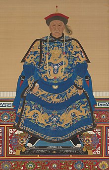 Full-face painted portrait of a severe-looking sitting man wearing a black-and-red round cap adorned with a peacock feather and dressed in dark blue robes decorated with four-clawed golden dragons.