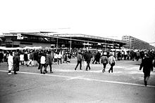 Photographie en noir et blanc de l'esplanade du stade Letná avec des dizaines de personnes marchant de dos.