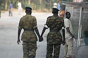 Two soldiers on patrol in the streets of Bujumbura, Burundi nonchalantly hold hands.