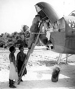 Armorers place a .50-caliber aircraft John Browning machine gun M2A1 in the nose of a 41st Bombardment Group North American B-25 Mitchell at the airfield on Hawkins Field as interested natives look on