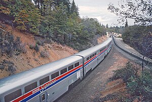 Silberne Triebwagen neben einem Hügel