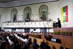 Barack Obama addressing the Burmese public during a speech at the University of Yangon on 19 November 2012. The vertical version of the Union Flag was depicted on the wall behind.