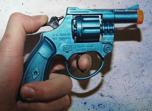 An orange-tipped cap gun with its hammer drawn back, 2008