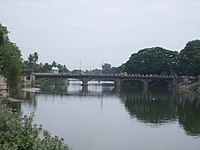 a bridge across a river with greenery in the background