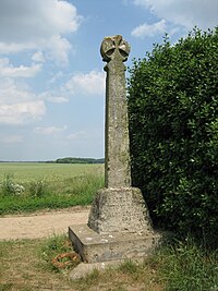 A stone post, topped with a cross, stands next to a bush in a field. An inscription on its base reads, "Battle of Towton Palm Sunday 1461"