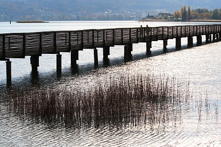 Der Holzsteg, rechts oben das nordöstliche Ufer von Hurden. Oberhalb der Passanten die Kapelle von Hurden. Dort endete die historische Holzbrücke (1360–1878).