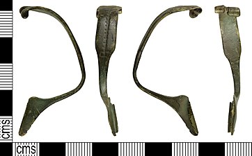 Брош од легуре бакра, од касног гвозденог доба до римског периода (око 25. - 75. године). Недостају игла и једно крило.