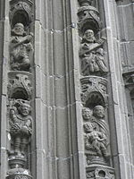 The scenes depicted here include Noah harvesting grapes from his vine and then Noah shown totally drunk! Above the biblical scenes, the voussure continues with the Evangelists. On the left side of the arch, Luke is shown with his attribute the lion and John with his attribute, a young boy. Mark and Matthew are depicted on the right side of the arch. After the Evangelists thirty one angels occupy the voussure, praying, playing instruments or holding their censers; a veritable "heavenly choir". Above the voussures are two sculptures. One is a small statue of a saint holding a book and the other is a saint with hands crossed against her chest.