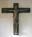 Das Mindener Bronzekreuz (1170/1020): Christus zwar mit geöffneten Augen, eher stehend als hängend, ohne Seitenwunde, dennoch mit Anzeichen des Leidens, eingesunkener Brust und heruntergezogenen Mundwinkeln.