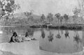 Mother and children sitting on the wall of a weir looking across the river to Mount Morgan, ca. 1894 (4582636449).jpg