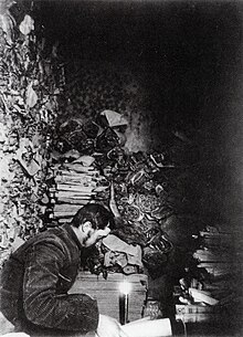 Paul Pelliot examining manuscripts in Cave 17 at Mogao Caves in 1908.jpg
