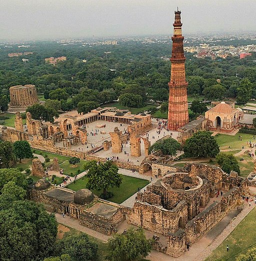 Delhi; Qutb-Minar: Blick nordwestwärts. Rechts der Qutb-Minar, links der Turmstumpf des Alai Minar; zwischen beiden die Ruine der Macht-des-Islam-Moschee