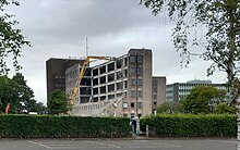 Six-storey office building made with prefabricated concrete panels and glass set in mature landscape