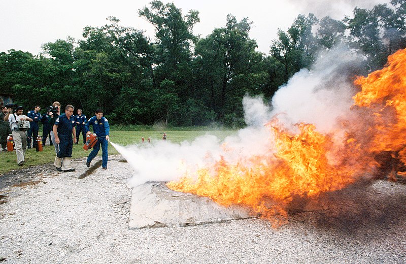 File:STS-41 crewmembers use fire extinguishers to control blaze at JSC's fire pit.jpg