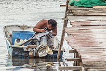 A Seletar man checking on his Outboard motor. Seletar The Orang Laut (25053867050).jpg