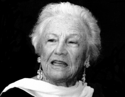 Black and white portrait of Silvana Lattmann. Head and shoulders of distinguished older woman with scarf draped elegantly over neck. She has short light-coloured hair and is wearing dangling earrings.