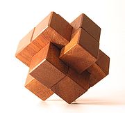 The Chinese wood knot, a notorious interlocking puzzle. In this particular version designed by Bill Cutler, five moves are needed before the first piece can be removed. SixPartWoodKnot.jpg