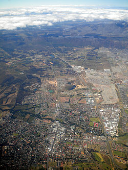 Aerfoto de Somerset West kun Hottentots-Holland Montoj kaj la Steenbras Digo en la fono