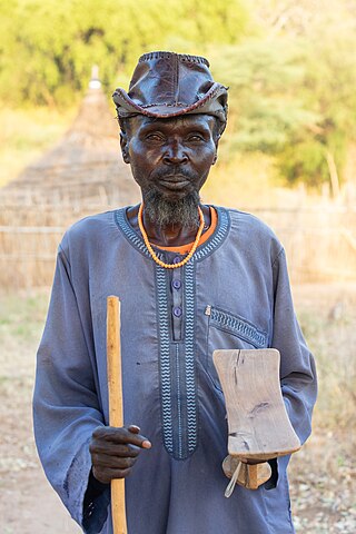 Portrait of an old man of the Laarim Tribe with a stick and a neck rest, Kimotong, South Sudan.