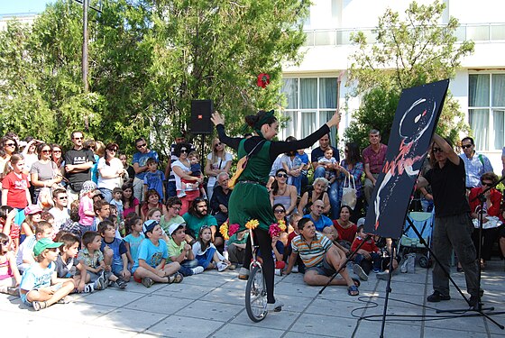 A unicyclist painter in action in a town square in Greece.