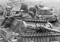 Photo en noir et blanc de deux chars avec des gens debout dans leur coupole ou assis dessus