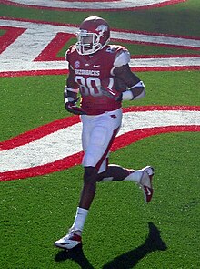 Gragg in a red and white Arkansas Razorbacks jersey on a football field, shot from a distance
