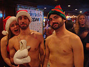 deux hommes et une femme partiellement dénudés et portant chapeau de père Noël et autres elfes