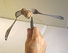 The total center of mass of the forks, cork, and toothpick is on top of the pen's tip Masocentro1.jpg