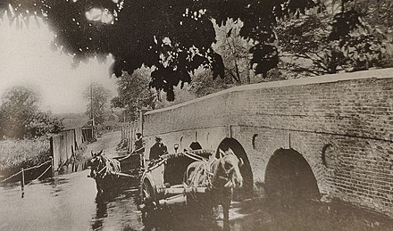 Old photograph of the bridge with two heavy one-horse carts crossing the adjacent ford.